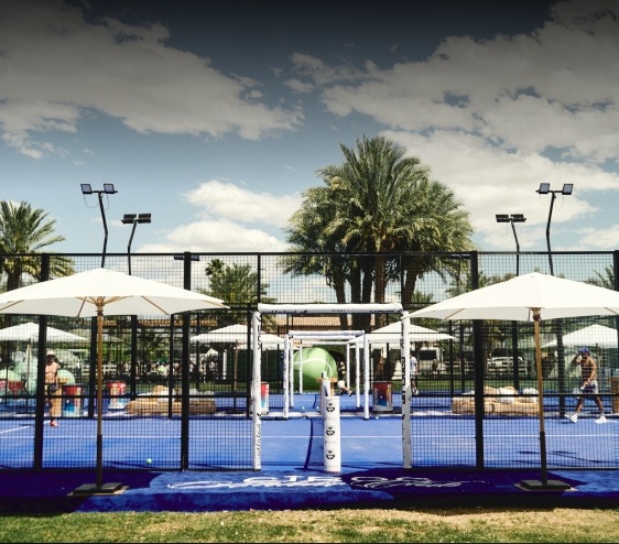 Padel courts with umbrellas and palm trees at the Coachella installation in Indio